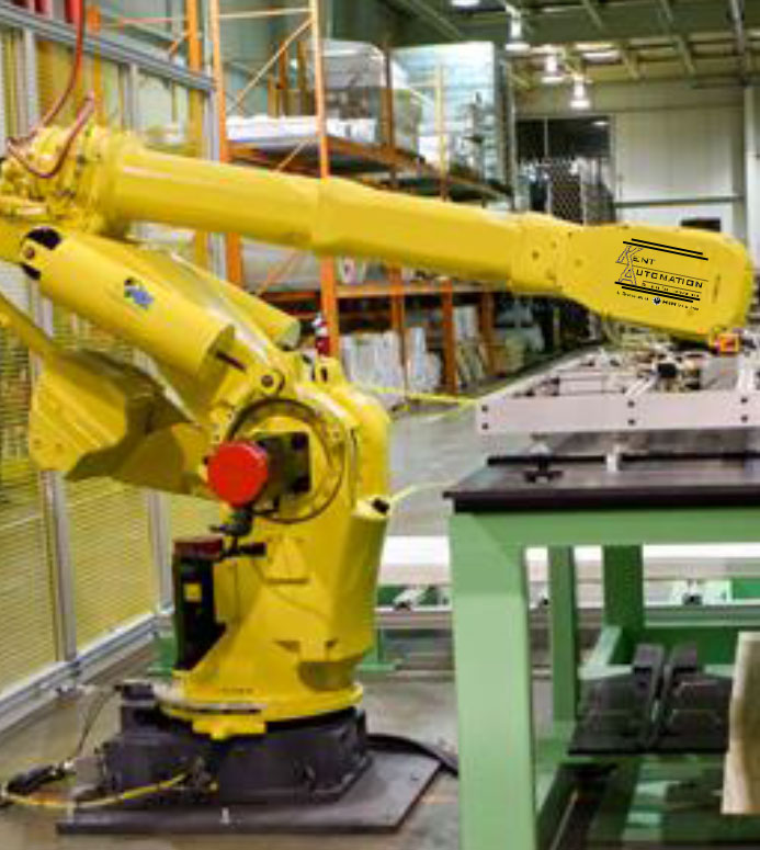 Yellow Kent Automation robotic cell arm positioned next to a production table and yellow perimeter safety fencing.